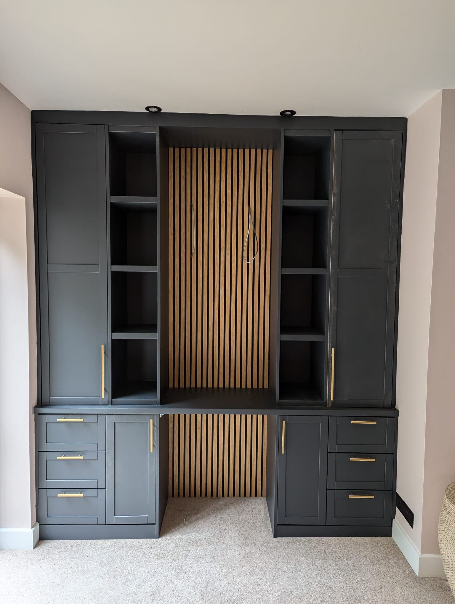 Bespoke fitted media wall with oak slat panelling and storage by Greenside Joinery